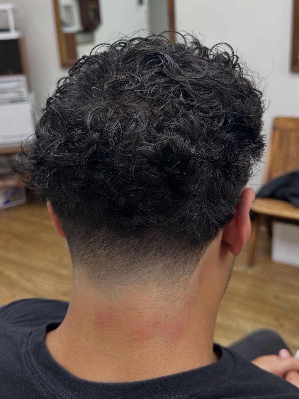Curly crop kept full on top with a clean taper through the nape